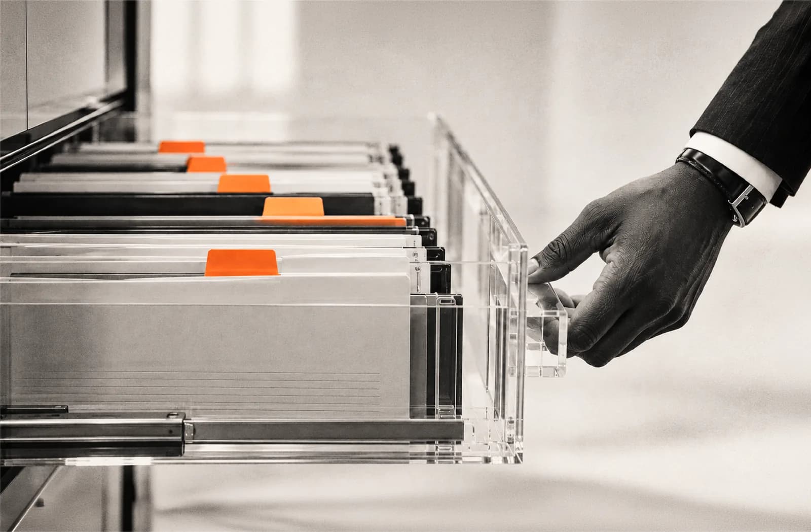 A hand opens a filing drawer full of folders